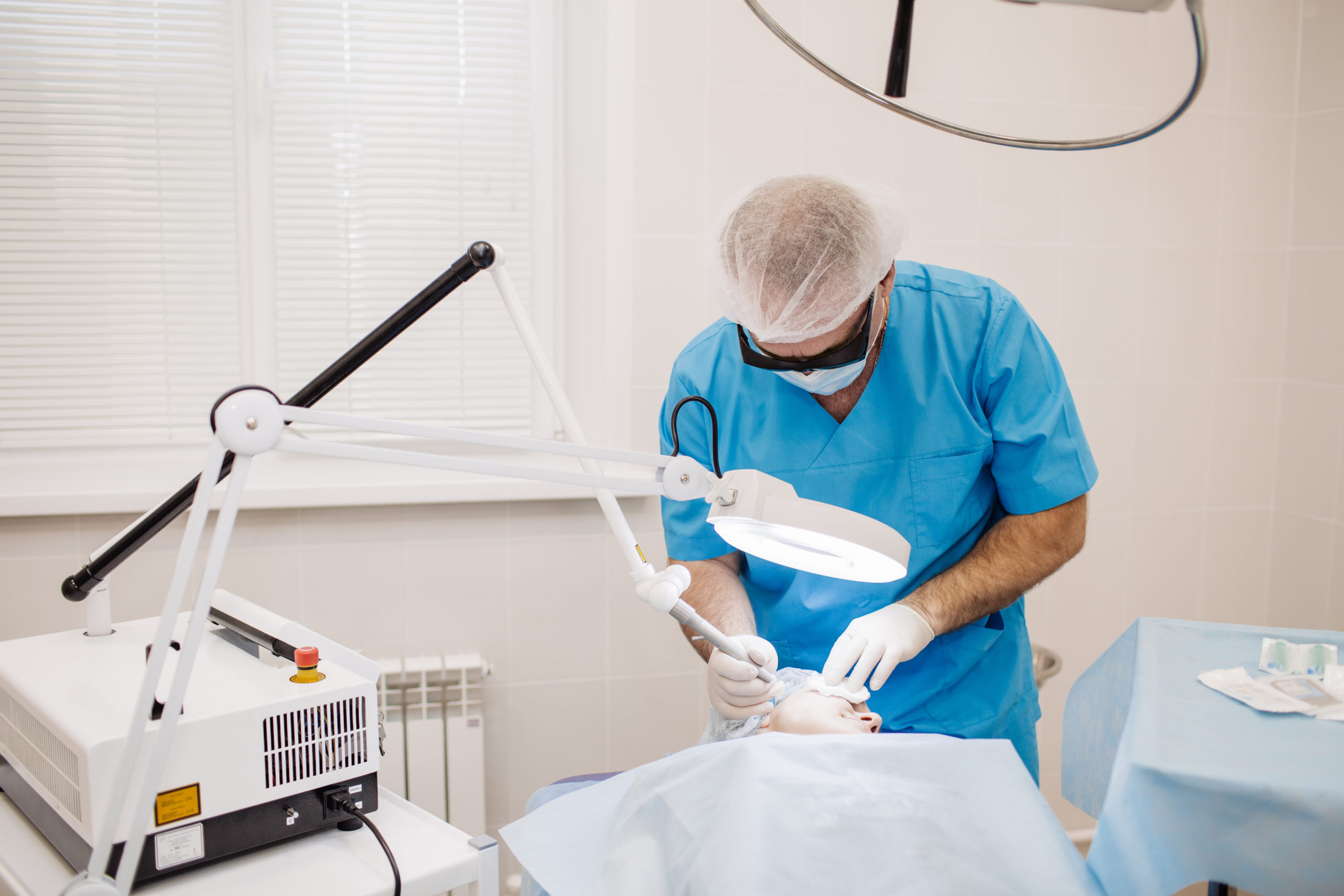 Doctor in safety glasses using laser for facial treatment in cosmetology clinic
